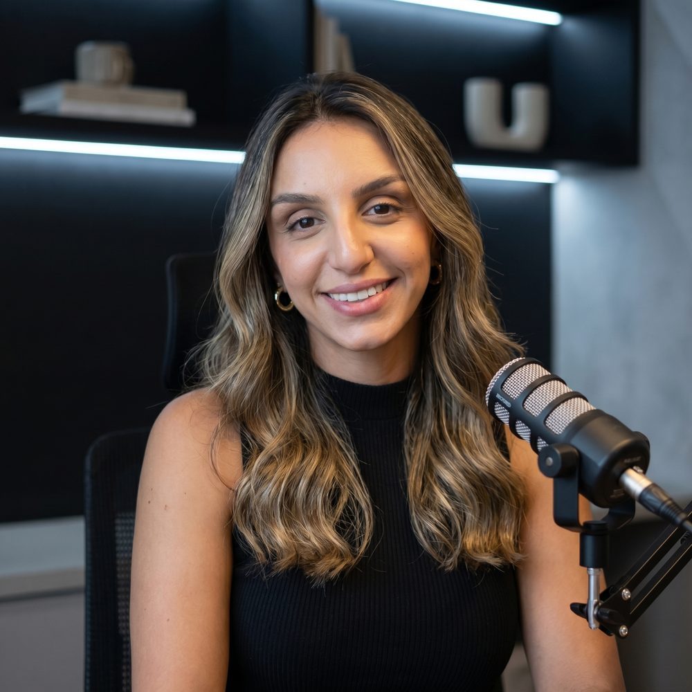 Natasha Mohamad sorrindo diante de um microfone de estúdio