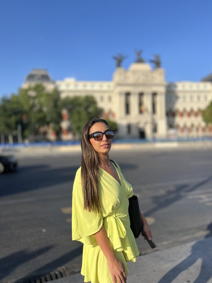 Natasha de vestido verde-limão, com um prédio histórico ao fundo